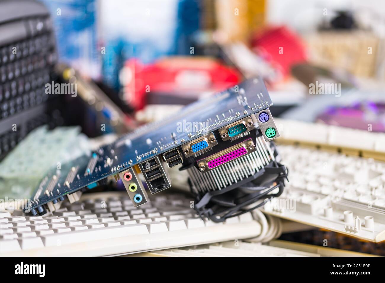 Scheda video di riserva su un mucchio di tastiere per computer. Parti hardware colorate. Scheda madre con scheda a circuito stampato, prese per connettori e refrigeratore. Rifiuti elettronici. Foto Stock