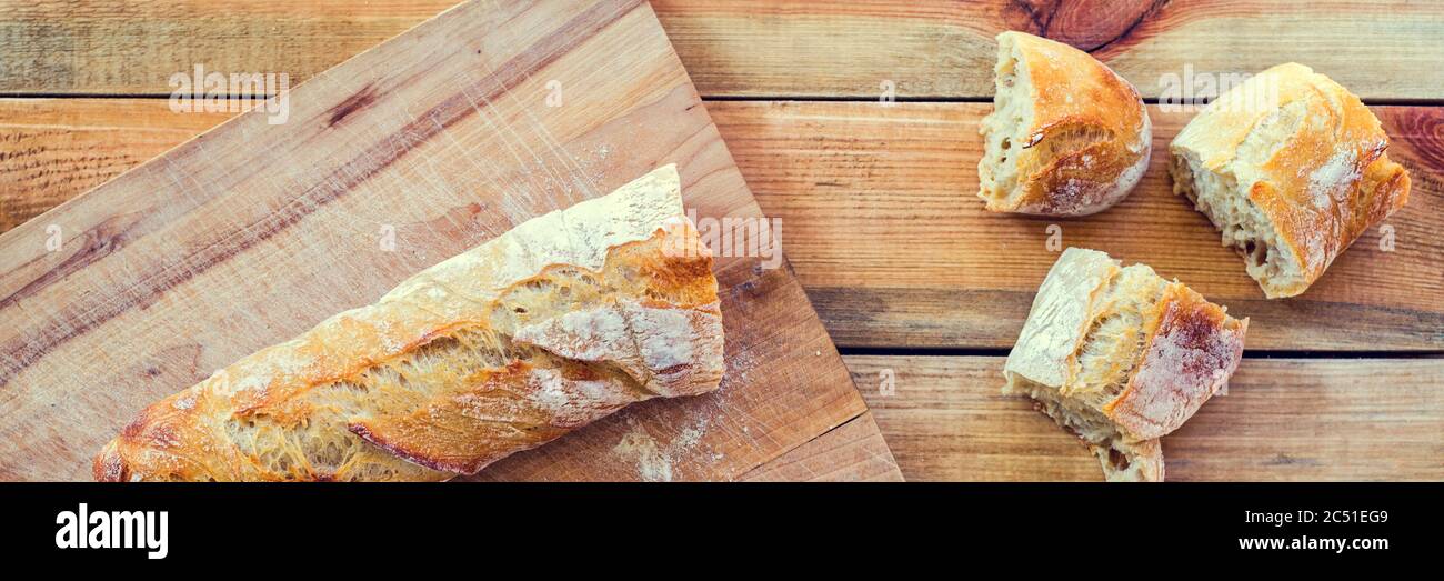 Baguette fresca pane su una tavola di legno, vista da sopra Foto Stock