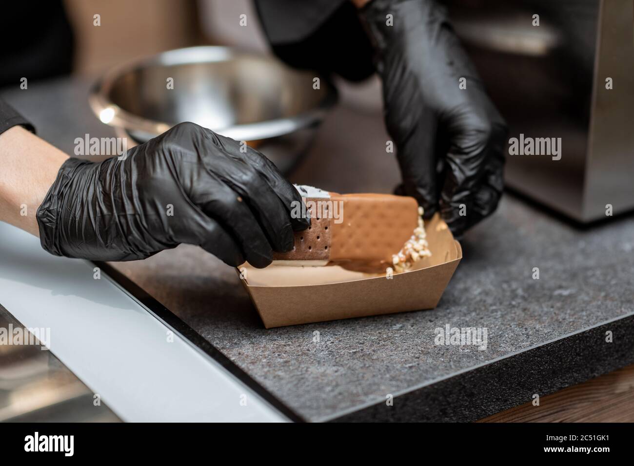 Chef che prepara gelato al cioccolato con guarnizioni in negozio, primo piano Foto Stock