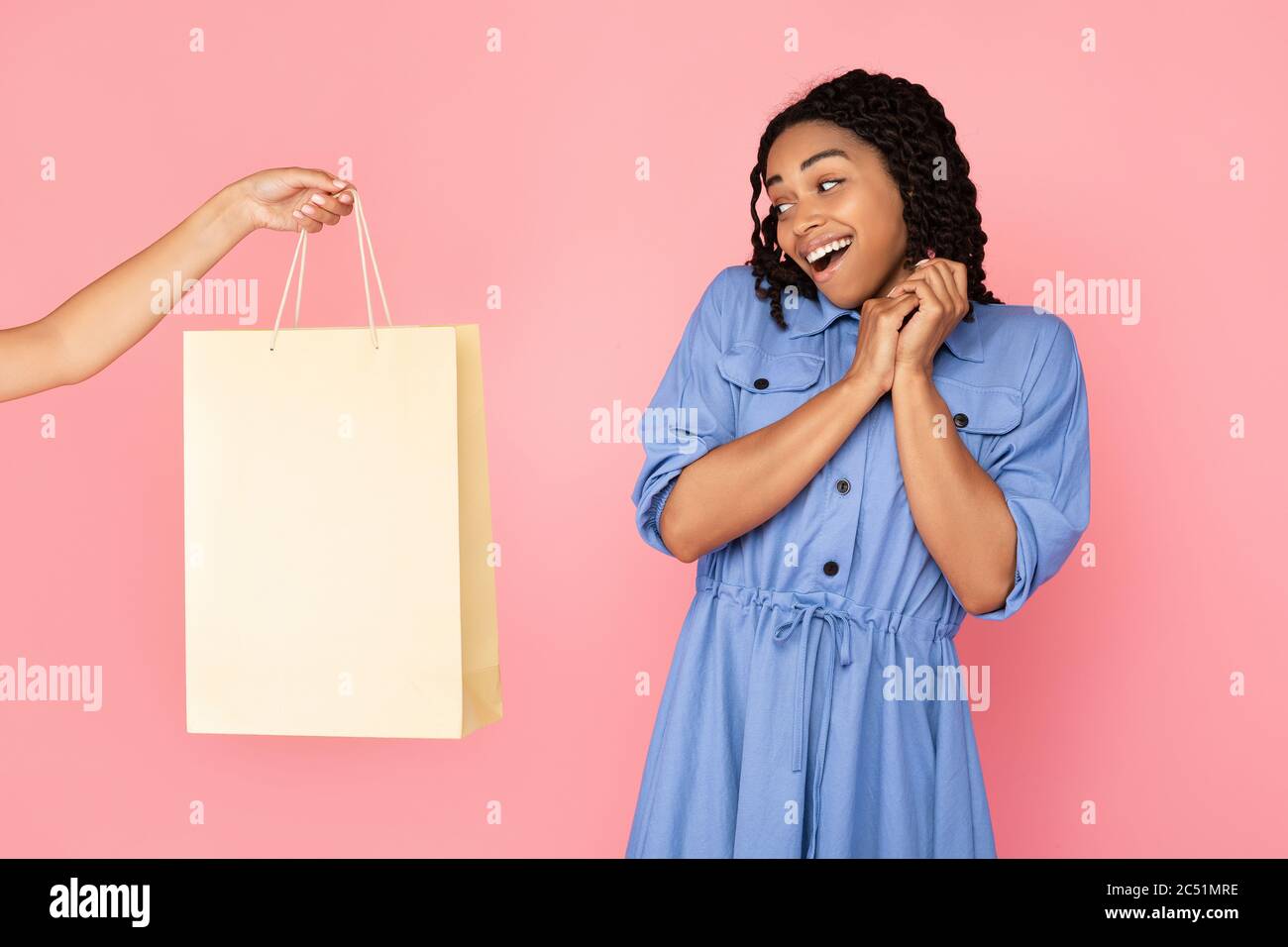 Mano che offre la borsa della spesa a Shopaholic Girl su sfondo rosa Foto Stock