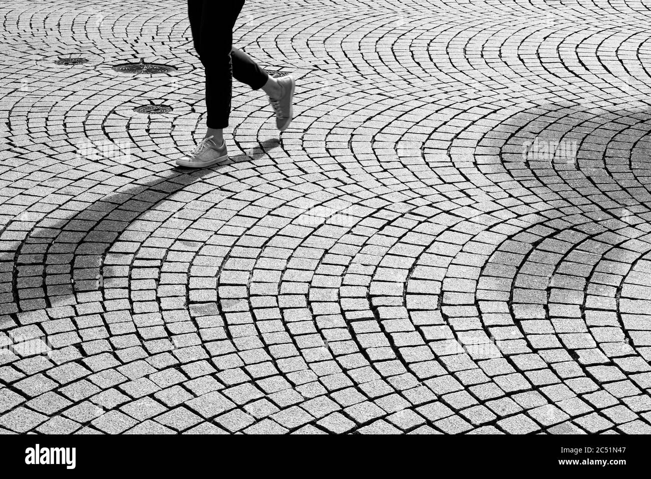 Piedi e gambe di una persona che cammina su strade acciottolate Foto Stock