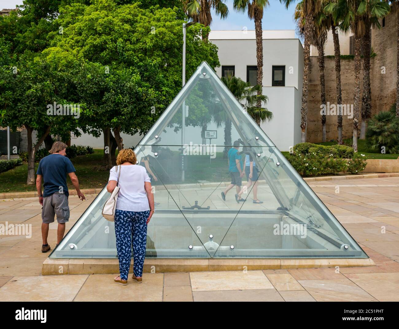 Turisti che guardano attraverso il vetro posto di osservazione a resti romani in Calle Alcazabilla, Malaga, Andalusia, Spagna Foto Stock