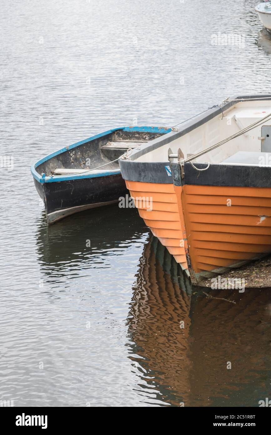 Grande e piccola barca ormeggiata sul fiume Fowey a Lostwithiel. Proprietario sconosciuto. Lavori in corso sul ponte della barca più grande. Metafora che rimane a galla. Foto Stock