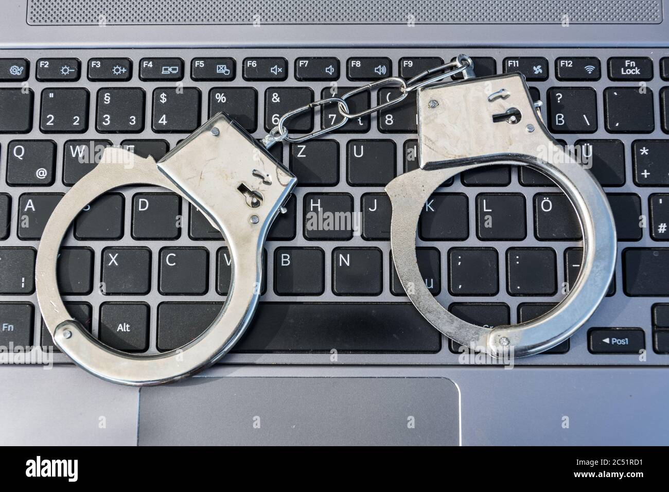 Manette che giacciono su una tastiera di computer simboleggiano il crimine informatico Foto Stock