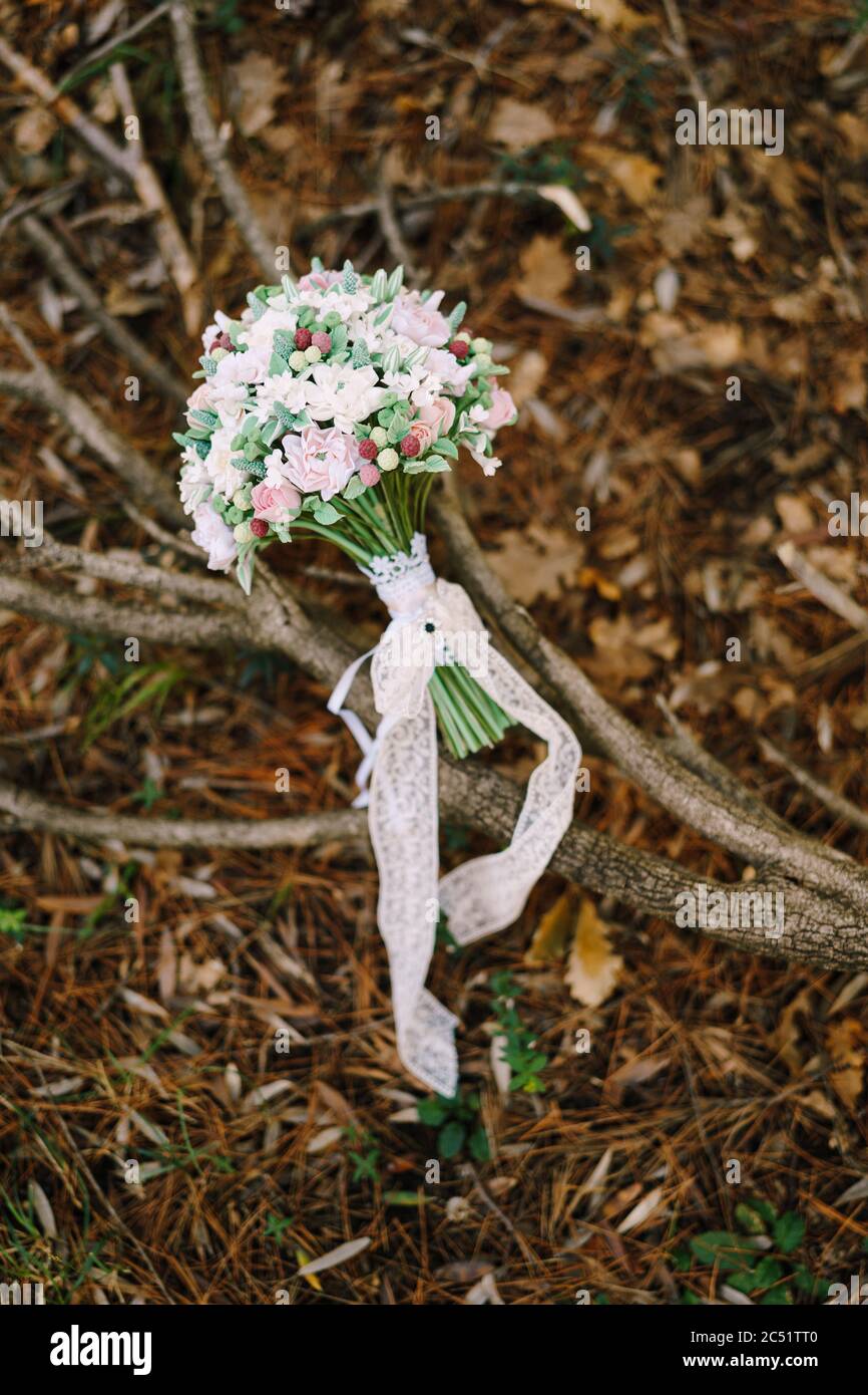 bouquet nuziale di rose bianche e rosa, bacche selvatiche, eustoma con nastri bianchi di pizzo sul brunch a secco, liingono a terra Foto Stock