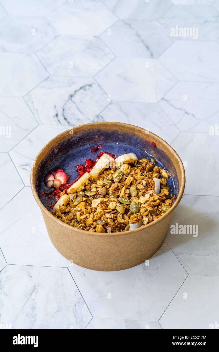 Ciotola Matcha blu con granola, mirtilli e banana / Smoothie Spirulina Blu sana in scatola di cartone Kraft di carta marrone. Supercibo sano organico. Foto Stock