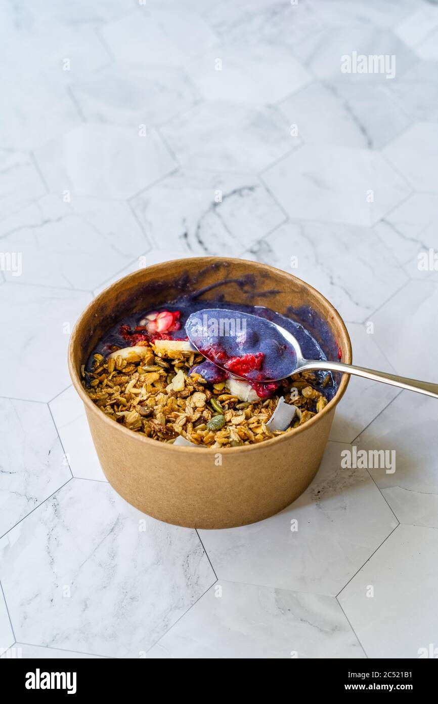 Ciotola Matcha blu con granola, mirtilli e banana / Smoothie Spirulina Blu sana in scatola di cartone Kraft di carta marrone. Supercibo sano organico. Foto Stock
