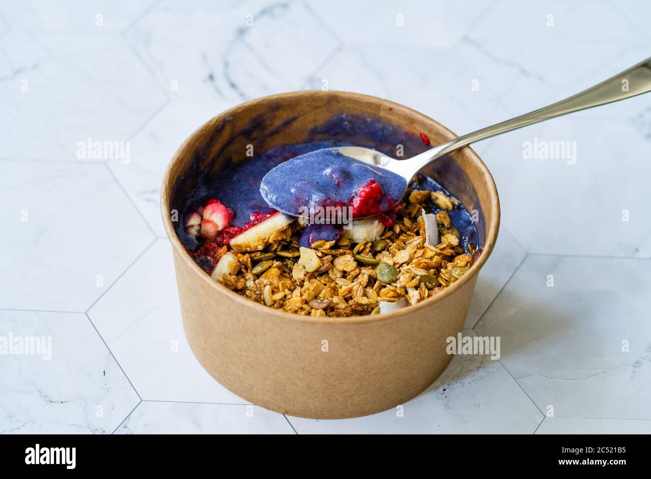 Ciotola Matcha blu con granola, mirtilli e banana / Smoothie Spirulina Blu sana in scatola di cartone Kraft di carta marrone. Supercibo sano organico. Foto Stock