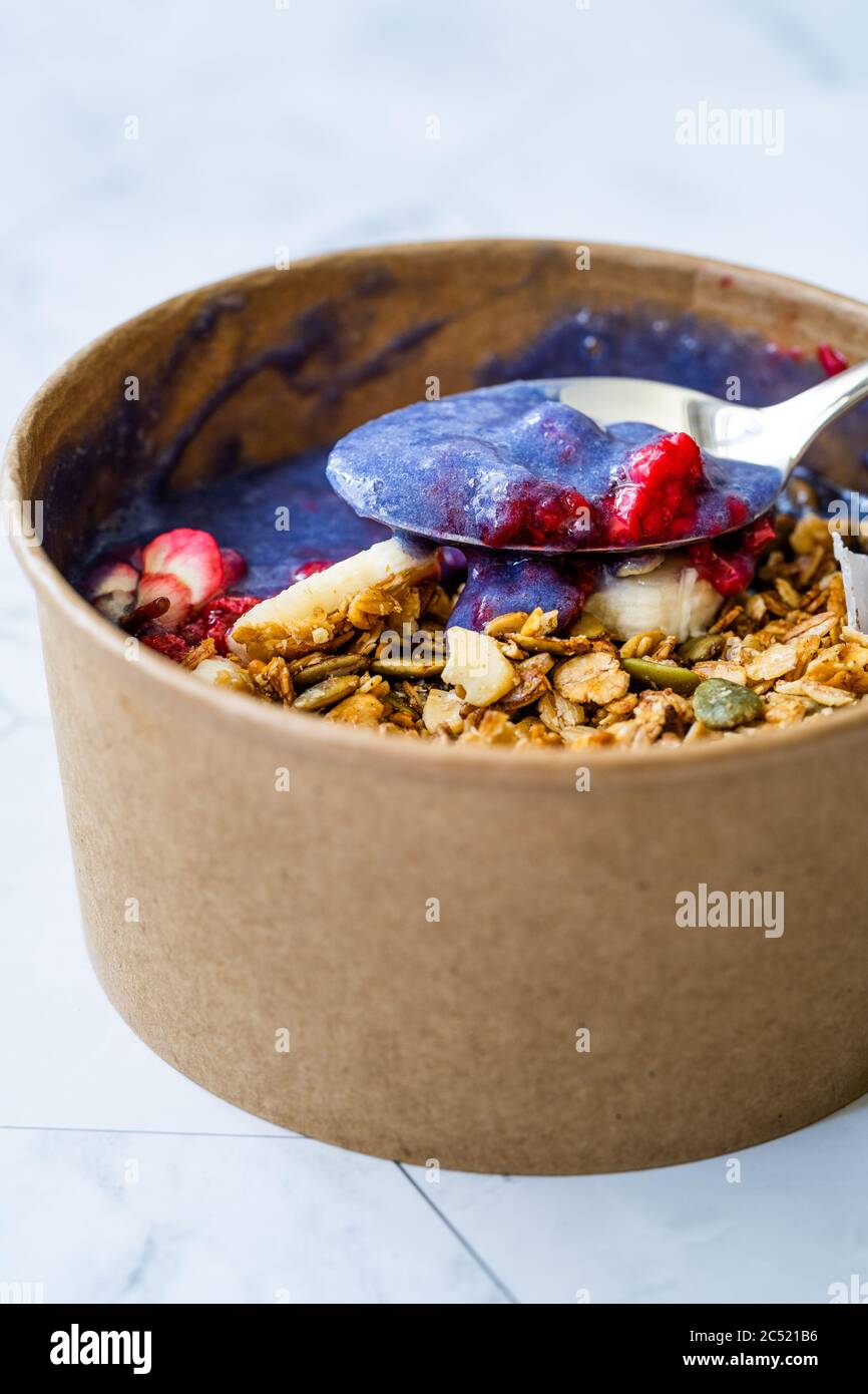 Ciotola Matcha blu con granola, mirtilli e banana / Smoothie Spirulina Blu sana in scatola di cartone Kraft di carta marrone. Supercibo sano organico. Foto Stock