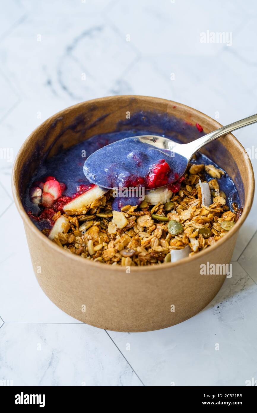 Ciotola Matcha blu con granola, mirtilli e banana / Smoothie Spirulina Blu sana in scatola di cartone Kraft di carta marrone. Supercibo sano organico. Foto Stock