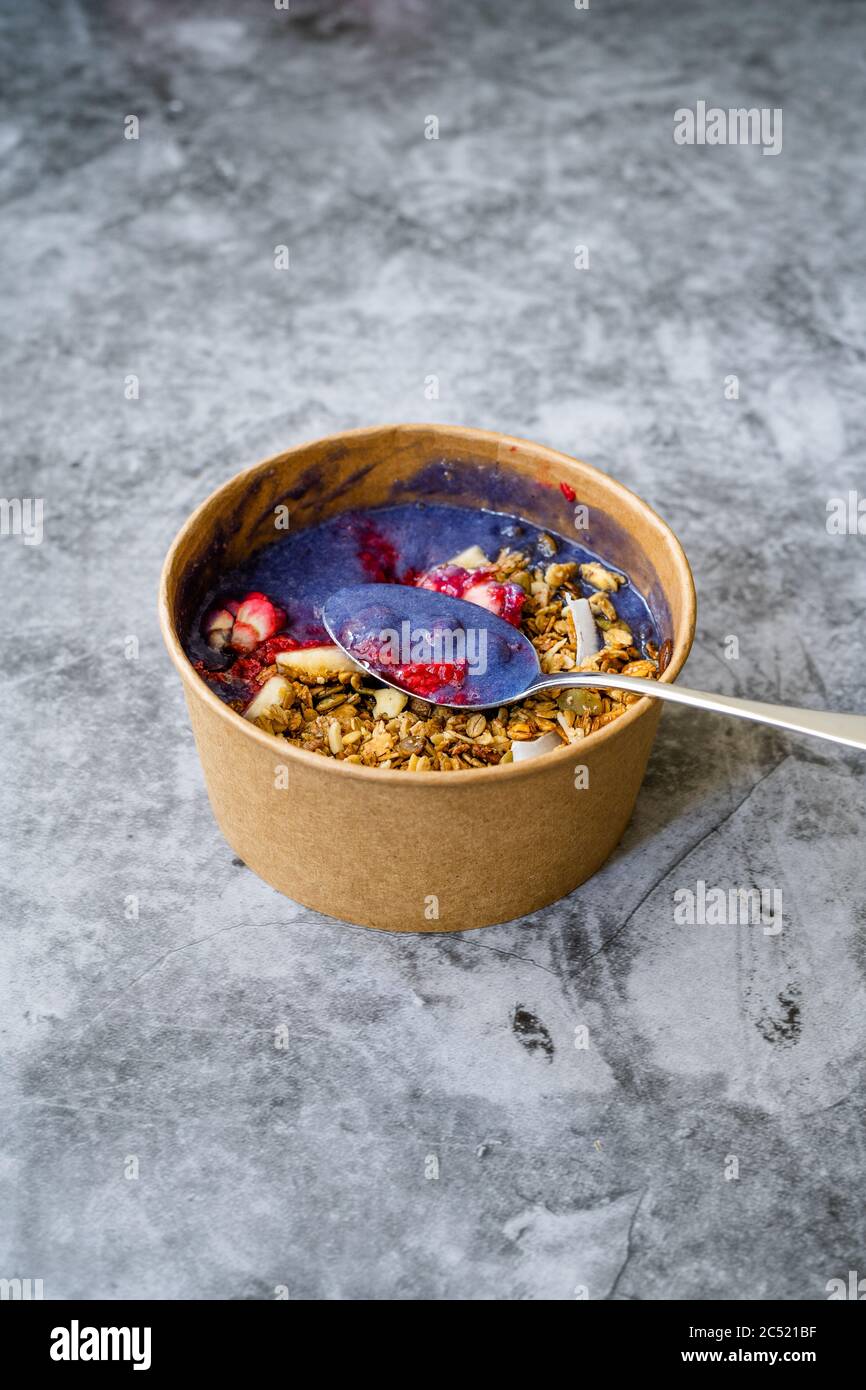 Ciotola Matcha blu con granola, mirtilli e banana / Smoothie Spirulina Blu sana in scatola di cartone Kraft di carta marrone. Supercibo sano organico. Foto Stock