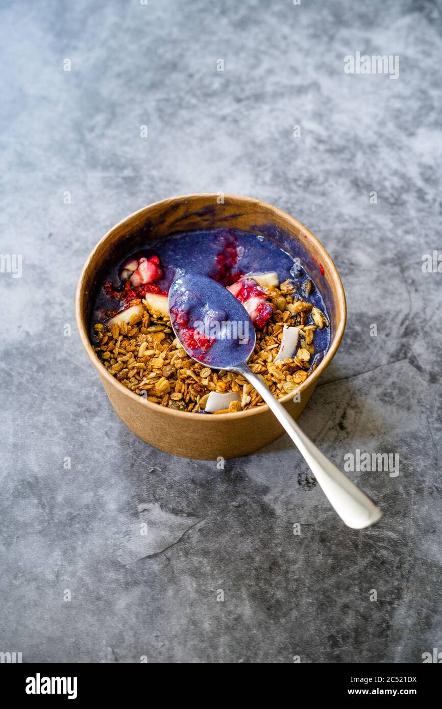 Ciotola Matcha blu con granola, mirtilli e banana / Smoothie Spirulina Blu sana in scatola di cartone Kraft di carta marrone. Supercibo sano organico. Foto Stock