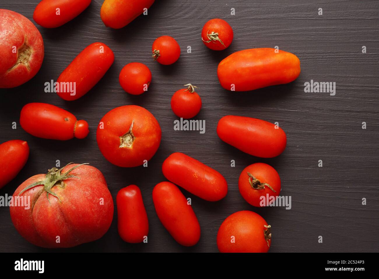 Pomodori lunghi organici su sfondo nero Foto Stock