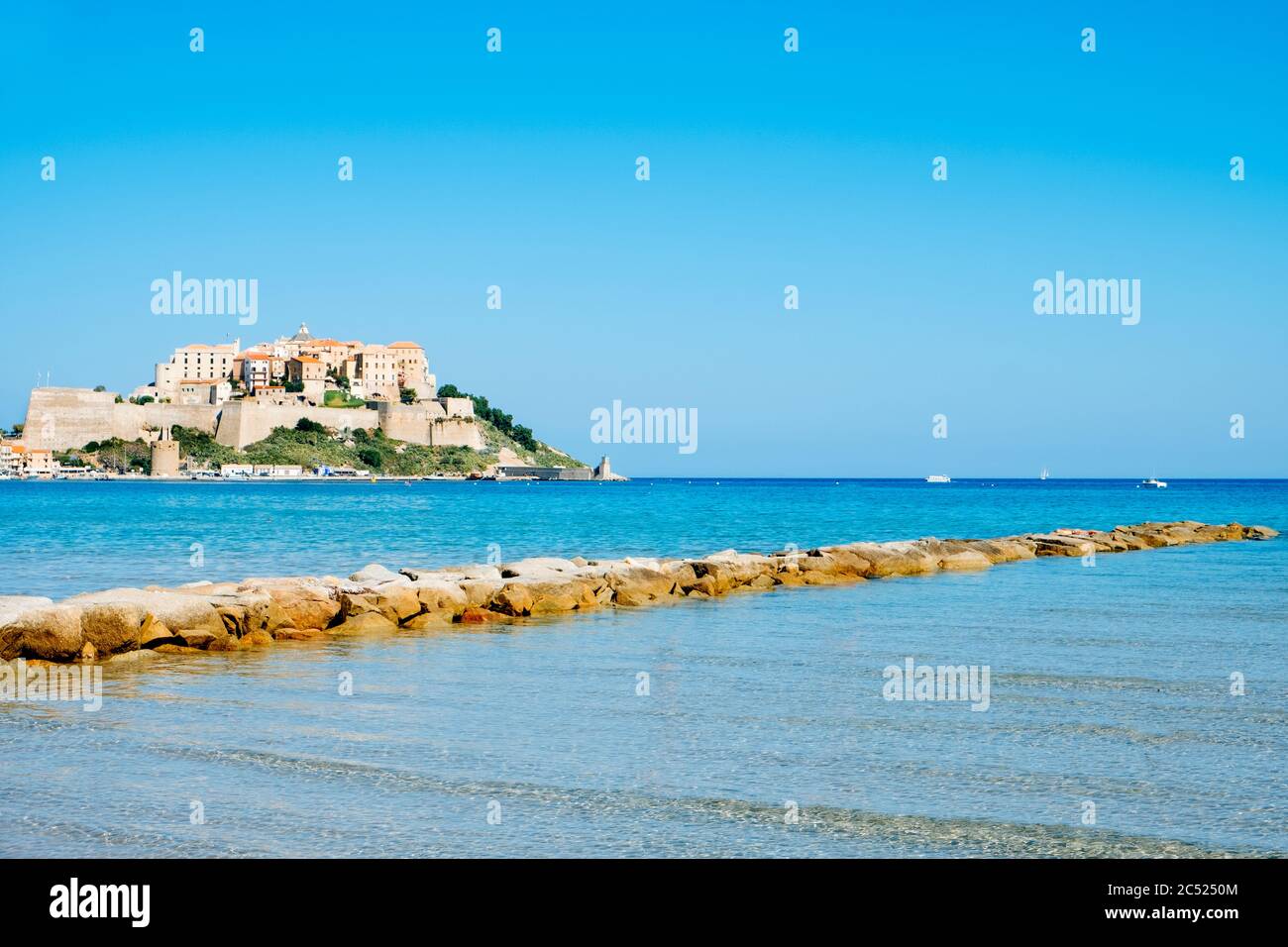 Una vista di Calvi, in Corsica, Francia, con la sua famosa cittadella sul rigth sulla cima di un promontorio, e il mare Mediterraneo in primo piano Foto Stock