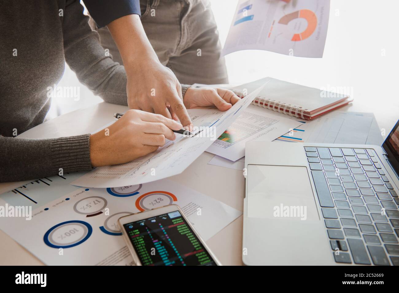 Il team aziendale analizza i dati di vendita e il grafico della crescita economica sul tavolo dell'ufficio con notebook e smartphone. Foto Stock