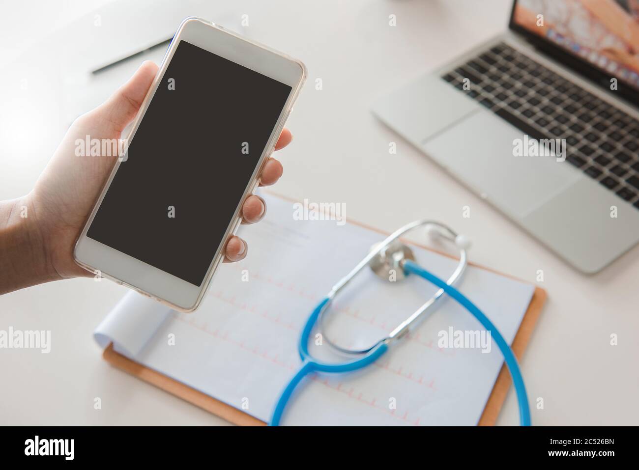 Medico che usa il telefono cellulare che legge rapporto trattamento su desk.healthcare e concetto di tecnologia. Foto Stock