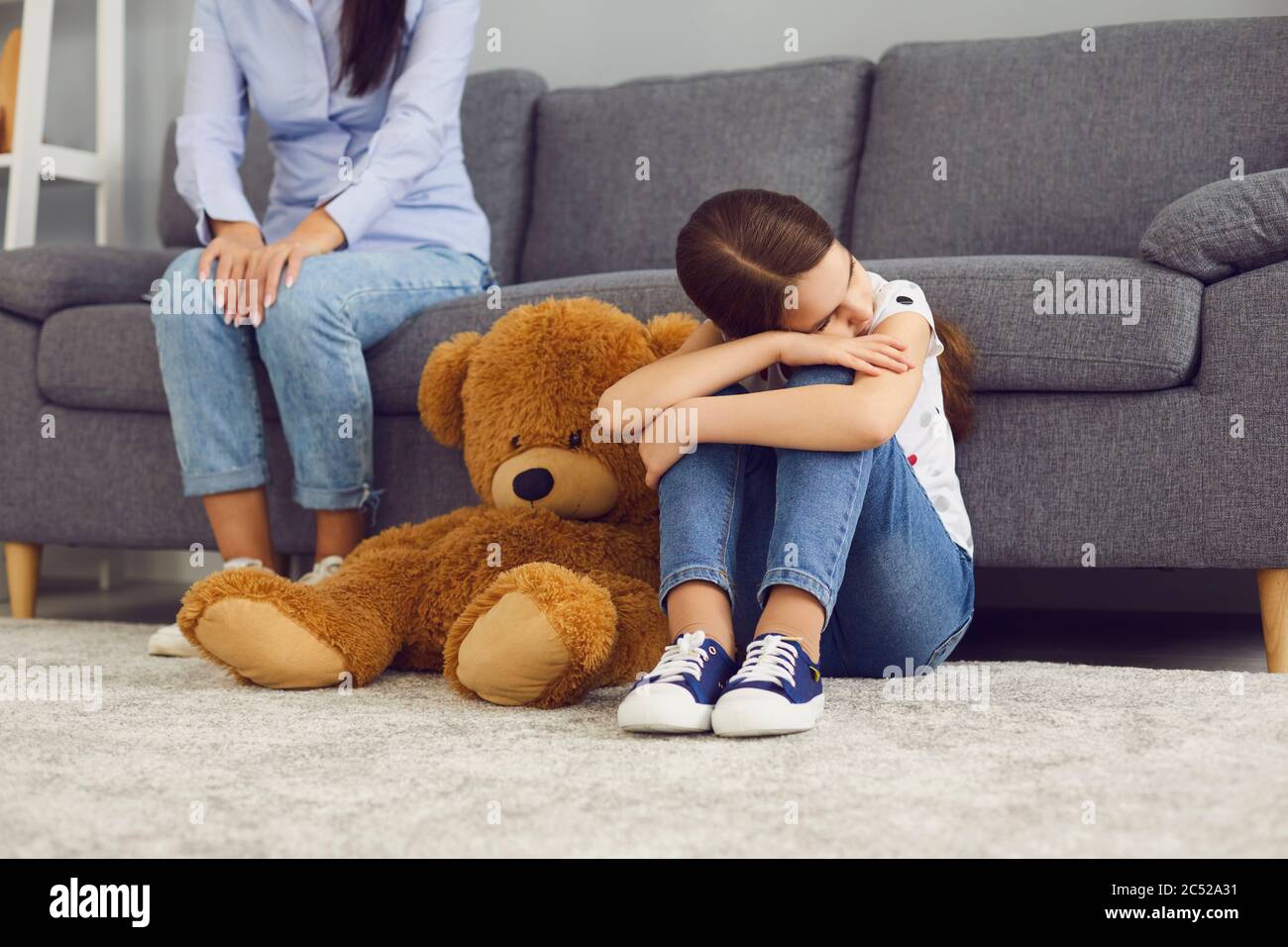 Triste bambino offeso seduto sul pavimento non parla con la madre in camera. Foto Stock