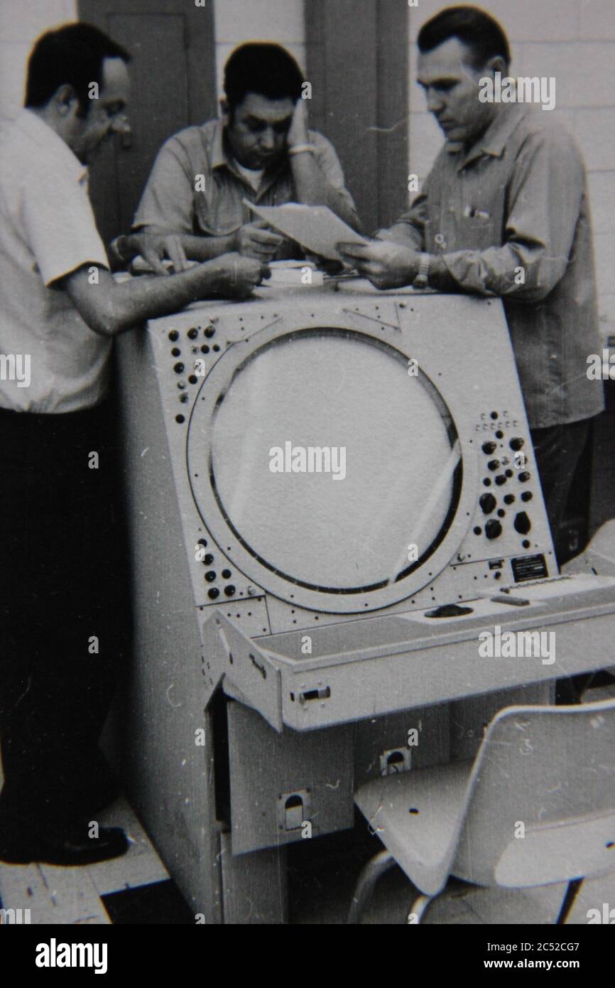 Fine anni 70 vintage nero e bianco stile di vita fotografia di tre uomini che parlano di un radar super computer assembly. Foto Stock