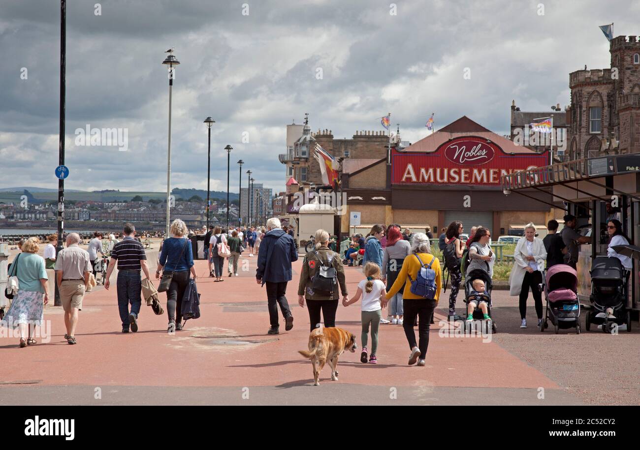 Portobello, Edimburgo, Scozia, Regno Unito. 30 giugno 2020. Oggi, 100 giorni dopo che il Regno Unito è entrato in Lockdown a causa della pandemia di Coronavirus Covid-19. Guardando la zona balneare di Portobello è difficile vedere che qualcosa è cambiato da prima della chiusura, le persone sono seduti insieme ai tavoli e sulla parete del lungomare, stanno comprando il loro caffè e spuntini dai chioschi e caffè. Anche se la temperatura era di 18 gradi a pranzo, c'erano meno persone sulla spiaggia che sulla passeggiata. Foto Stock