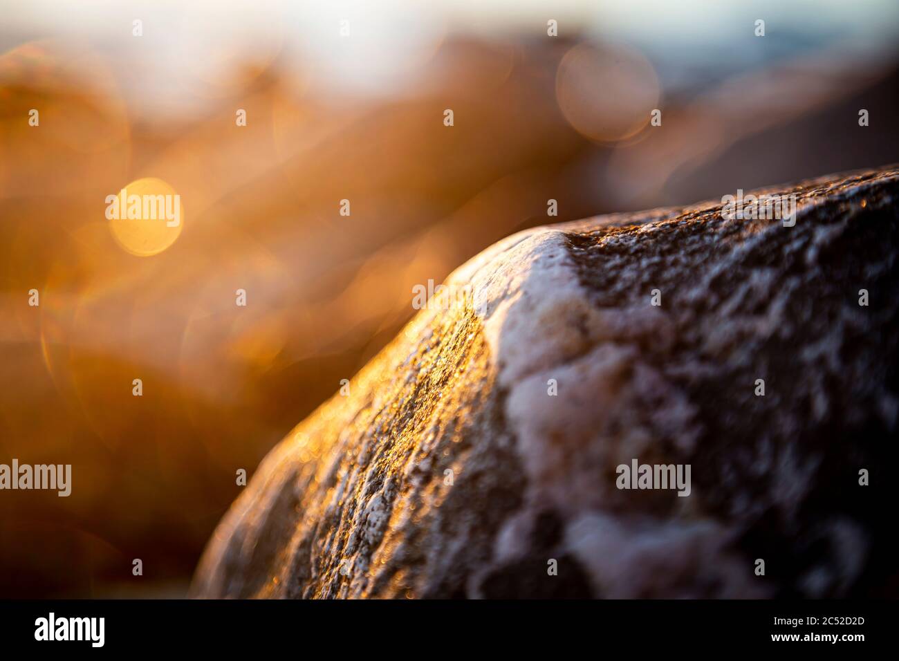 Pietre e rocce sassose sulla spiaggia illuminate al sole nella serata closeup, texture tramonto e alba Foto Stock