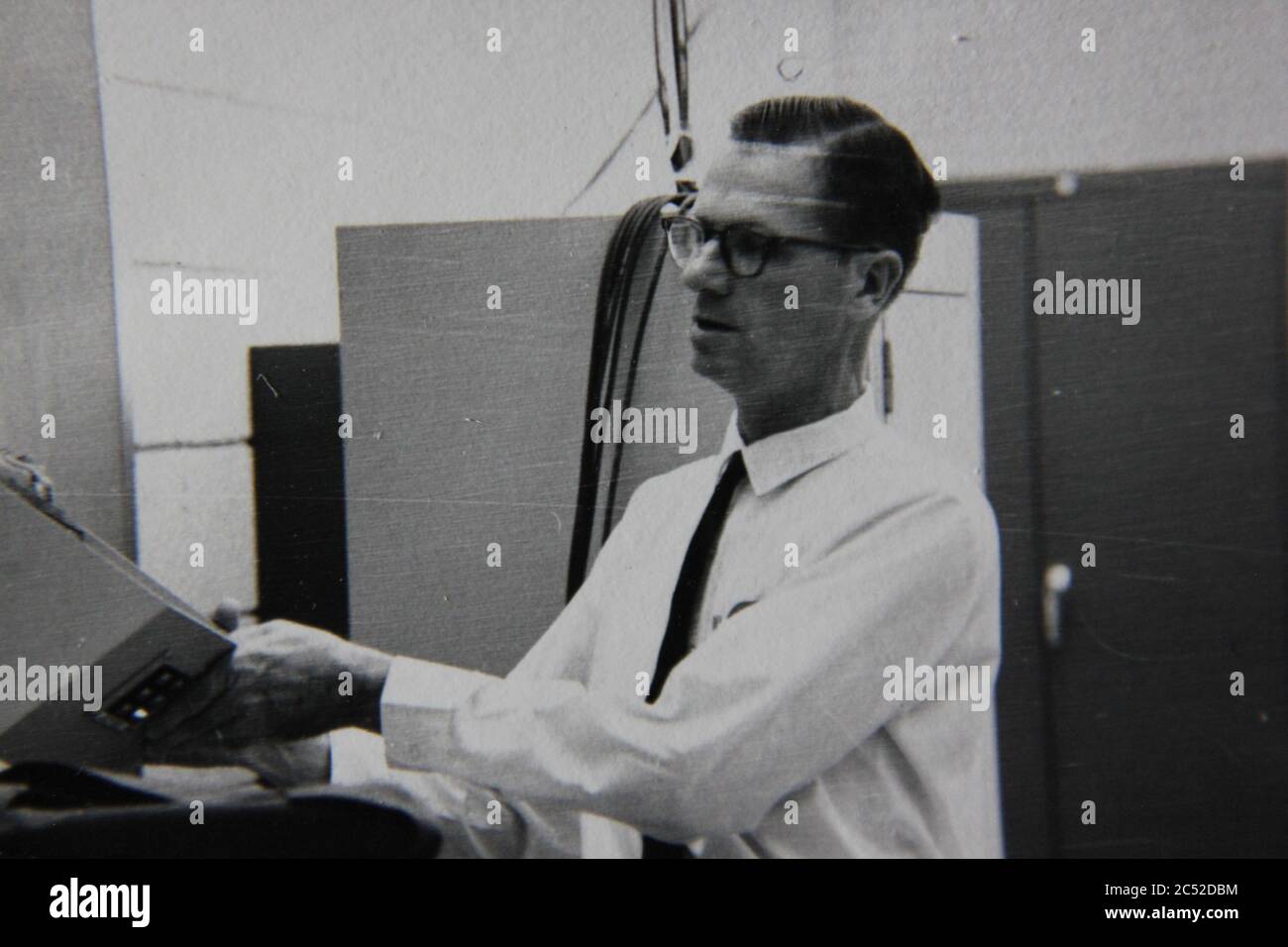 Fine anni '70 vintage nero e bianco stile di vita fotografia di un uomo professionale che gestisce un super computer in ufficio. Foto Stock
