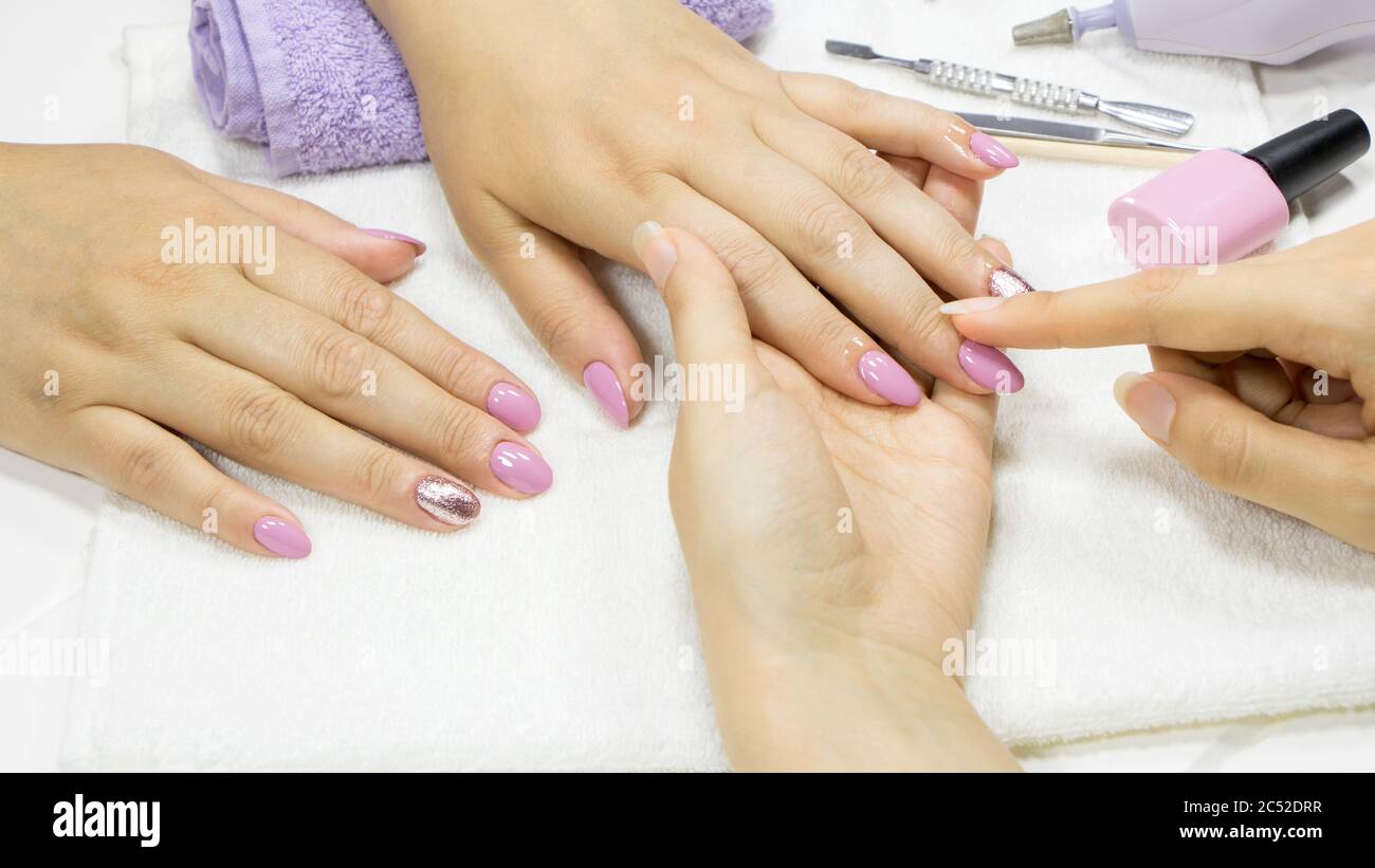 Applicare olio alla cuticola. Manicure, cura delle unghie. Il manicurista mette l'olio idratante sulla cuticola con le dita. Salone di unghie, procedura, SPA. Pelle Foto Stock