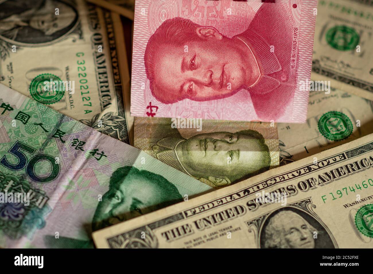 Concetto di guerra commerciale USA-Cina. Banconote in renminbi cinese (yuan) con banconote verdi in dollari americani. Illustra il commercio, il commercio, le importazioni, le esportazioni. Foto Stock