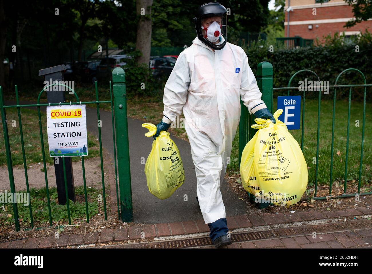 Un lavoratore del consiglio comunale trasporta i rifiuti da un centro di test del coronavirus a Spinney Hill Park a Leicester, dopo che il segretario di salute Matt Hancock ha imposto un blocco locale a seguito di un picco nei casi del coronavirus nella città. Foto Stock