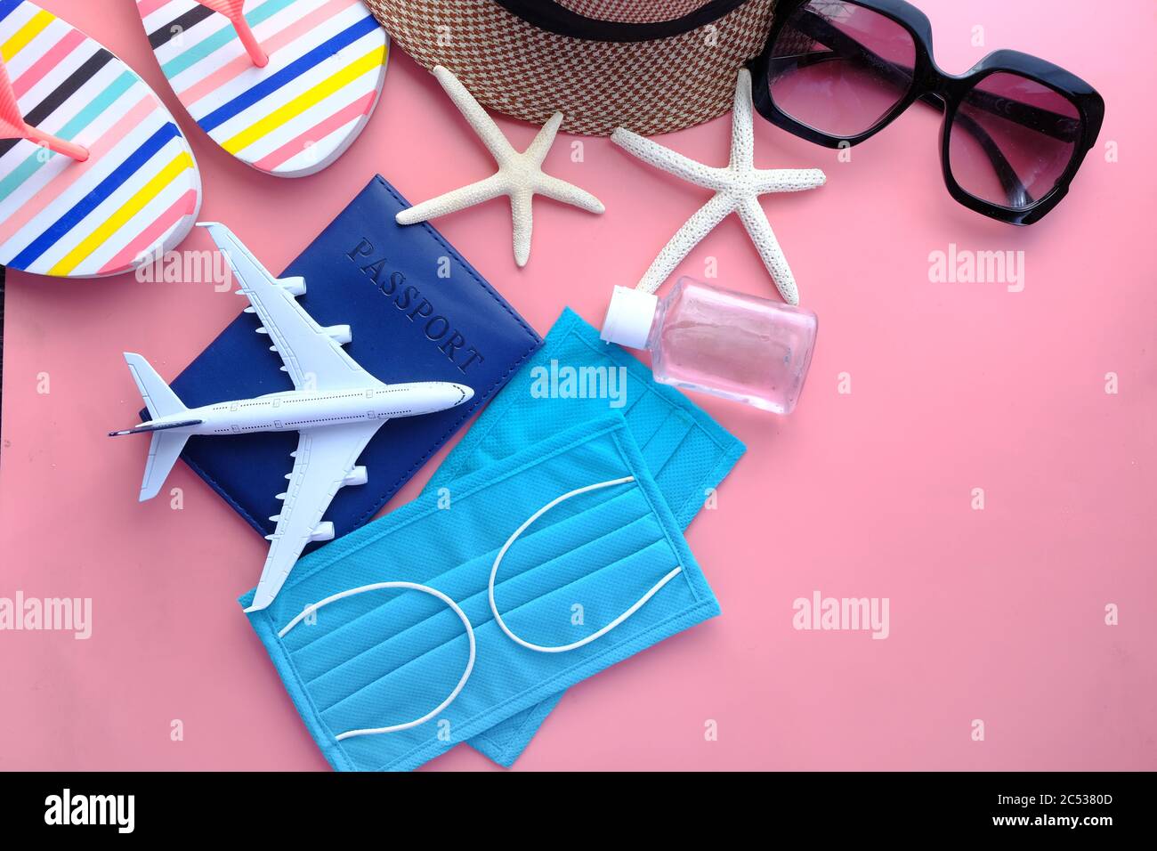 accessori da spiaggia con maschera protettiva e igienizzatore su sfondo rosa. Foto Stock