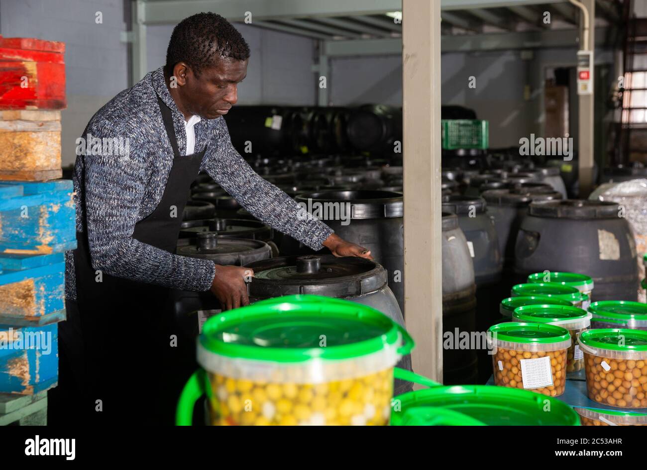 L'uomo africano lavoratore di olive in salamoia di impilamento di fabbrica  botti di plastica, controllando il processo di fermentazione Foto stock -  Alamy