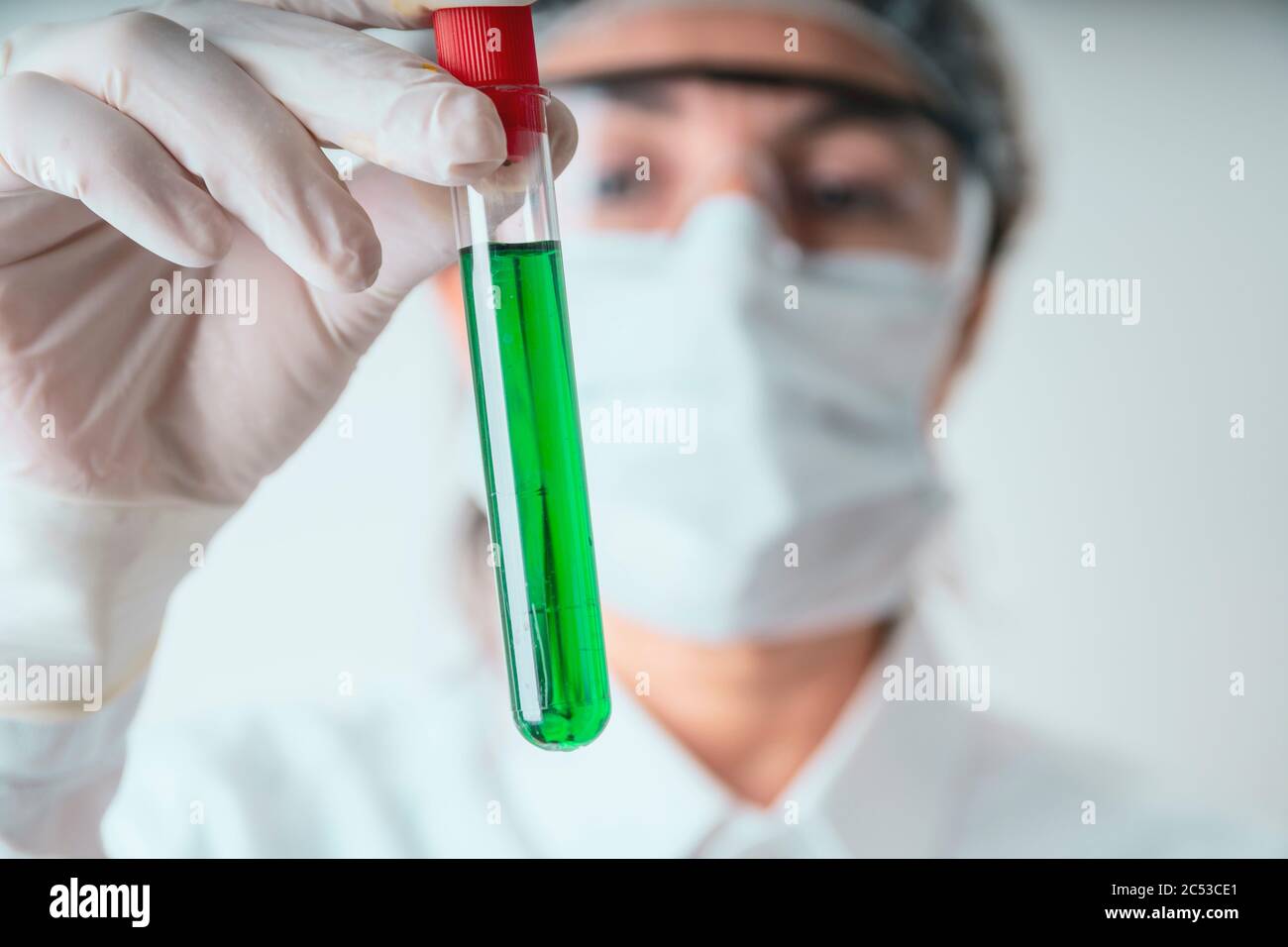 La donna laboratoriana sta mostrando una provetta verde per test liquidi per la ricerca sui vaccini nel laboratorio del coronavirus. Foto Stock