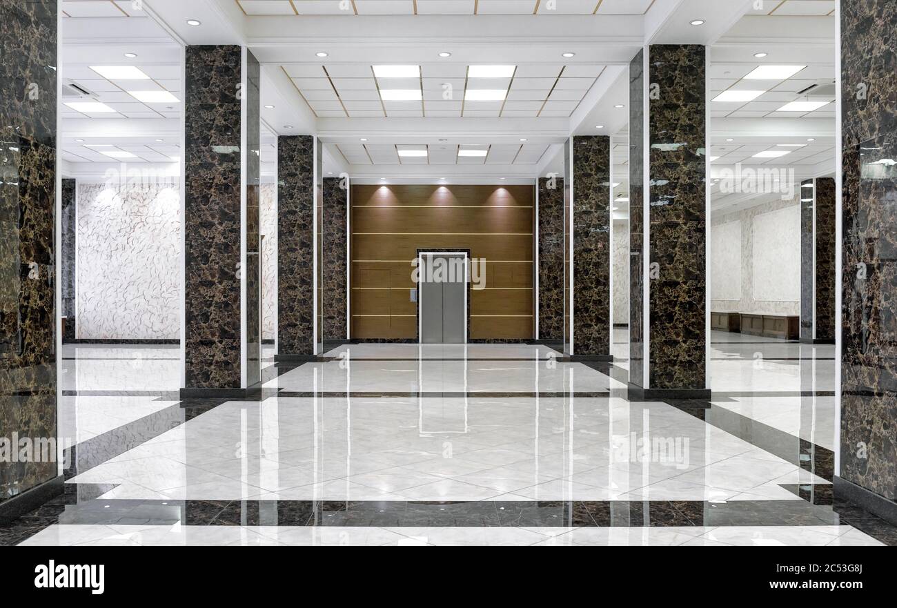 Interni in marmo di una lussuosa lobby di aziende o hotel. Corridoio aziendale pulito con piastrelle di pavimento. Pavimento lucido con riflessi dopo il professionale c Foto Stock
