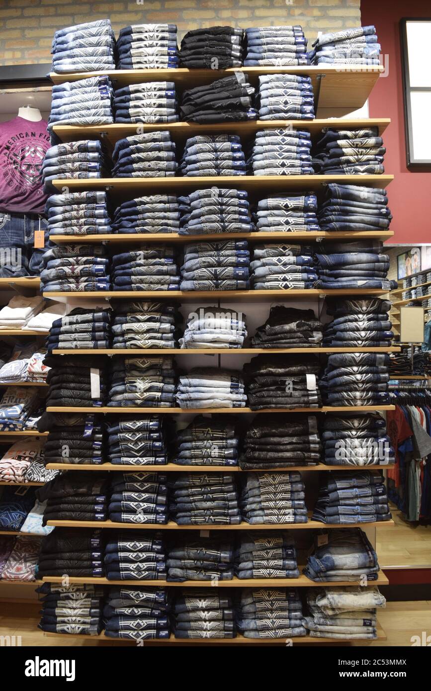 FRESNO, STATI UNITI - 08 giugno 2020: Un ripiano alto pieno di jeans blu piegati casual e rilassati che sono sbiaditi e strappati con colori più chiari e variabili per Foto Stock