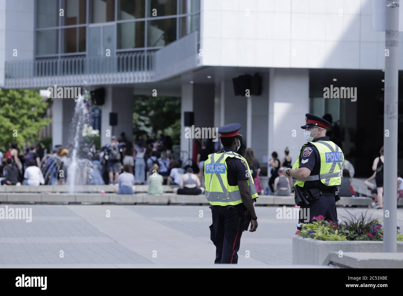 Due ufficiali di polizia osservano mentre la gente si riunisce per la protesta pacifica contro il razzismo di BLM al Municipio di Hamilton, Ontario Canada Foto Stock