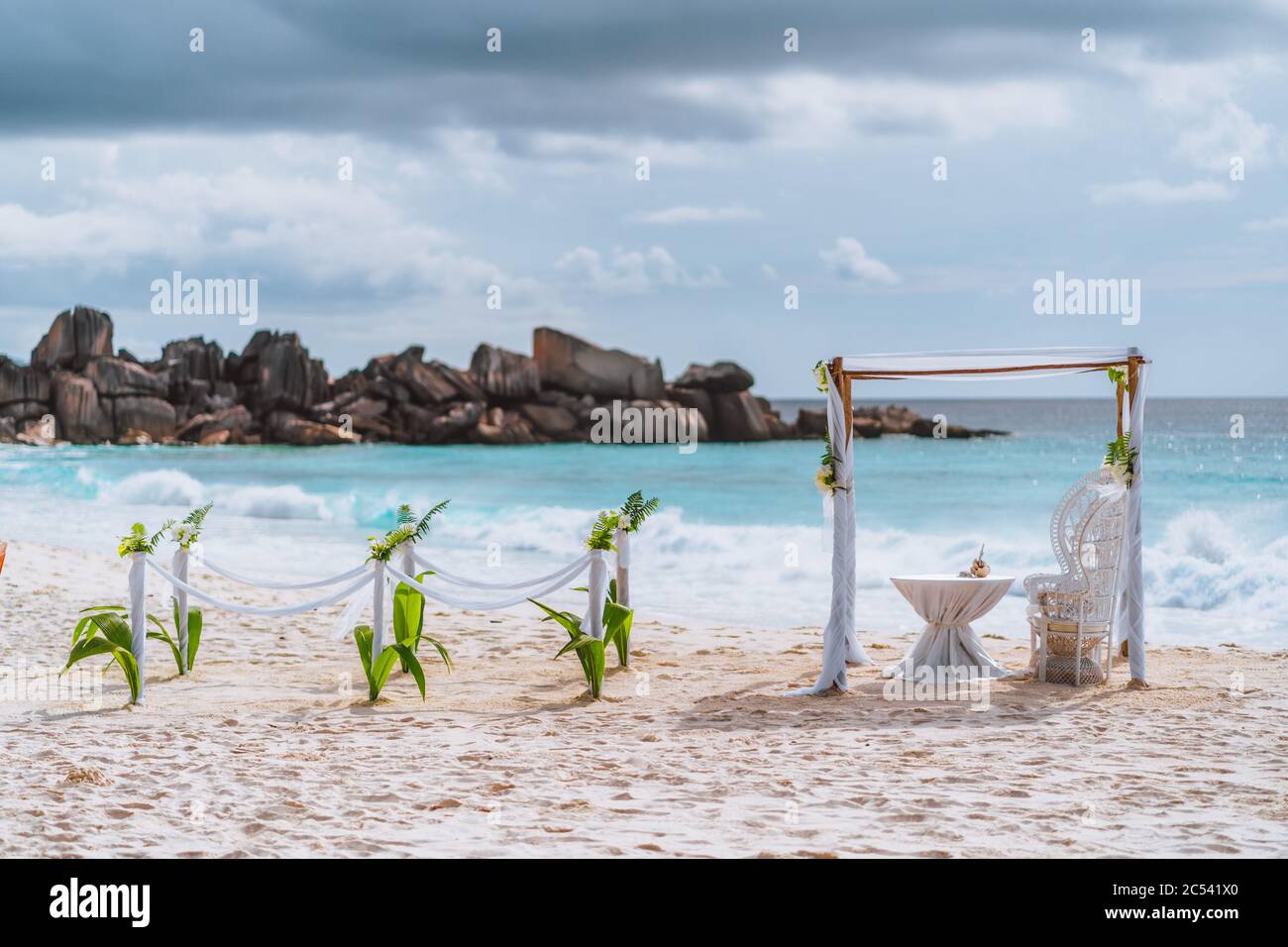 Decorato romantico ambiente per matrimoni con tavolo e sedie sulla spiaggia tropicale sabbiosa con luce del tramonto con nuvole di luna sullo sfondo, isole Seychelles. Foto Stock