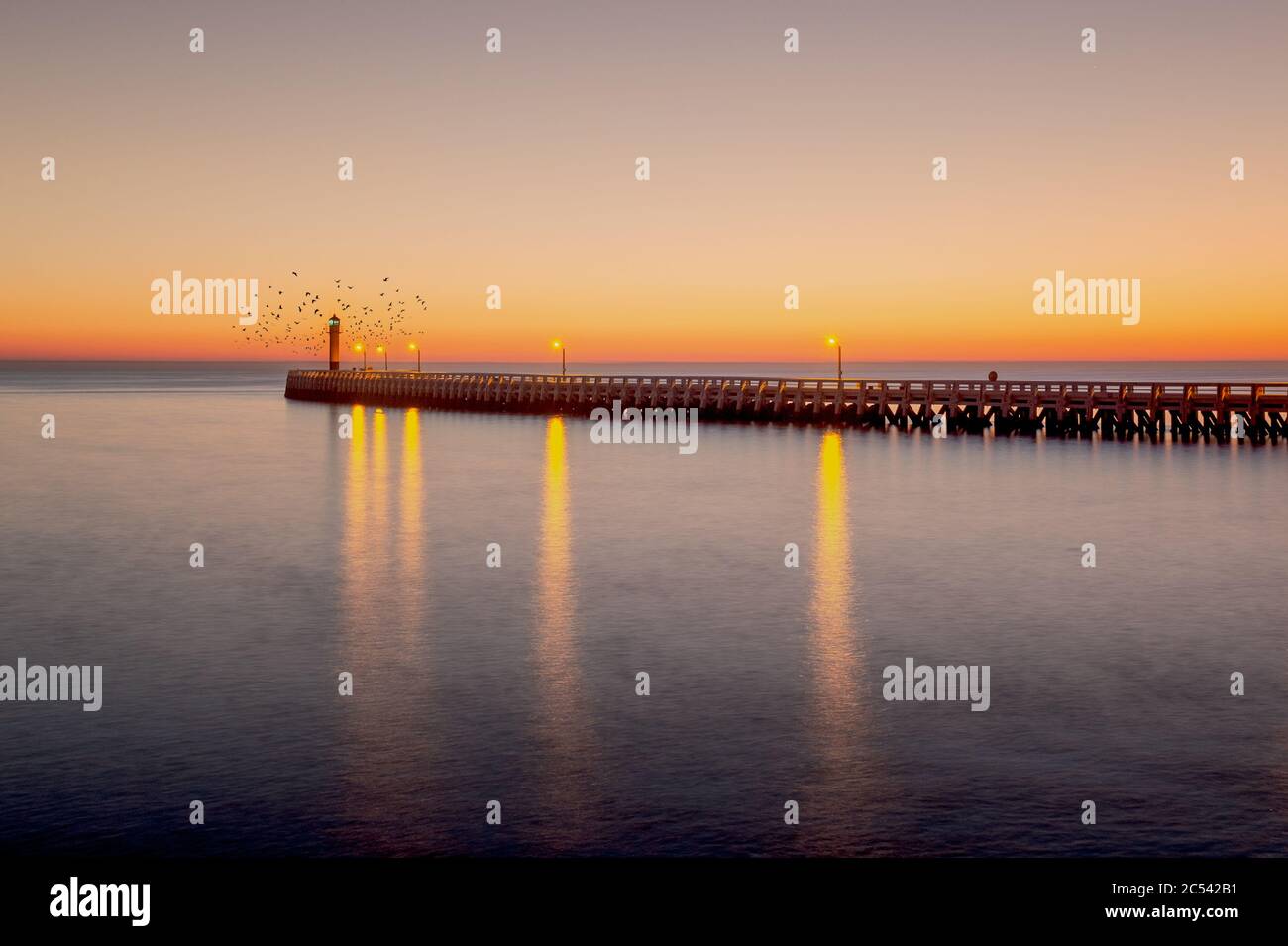 Molo e faro di Nieuwpoort (Belgio) durante il tramonto Foto Stock