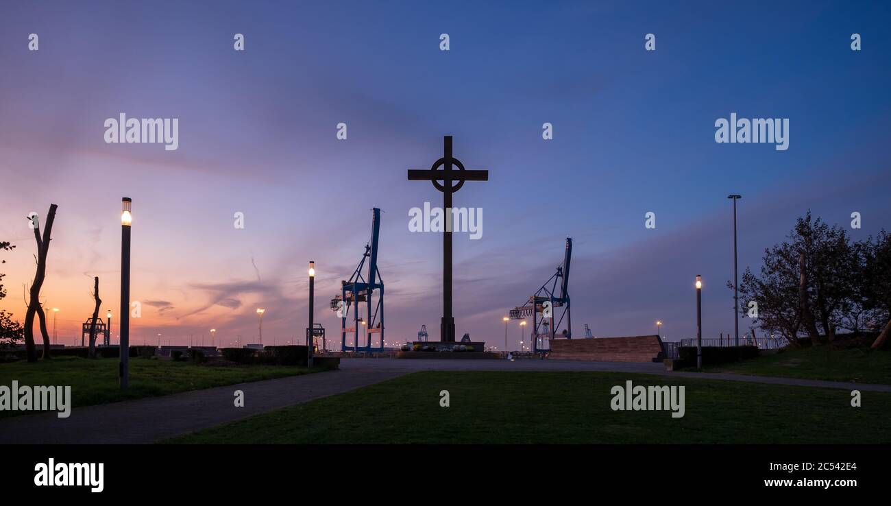 Vista silhouette del monumento chiamato Visserkruis e gru portuali nel porto internazionale di Zeebrugge Foto Stock