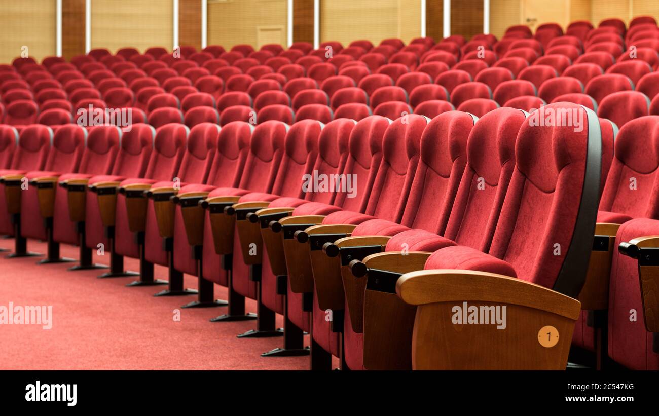 File di posti a sedere rossi. Vista panoramica di una sala cinema vuota. Poltrone confortevoli all'interno del moderno cinema. Foto Stock
