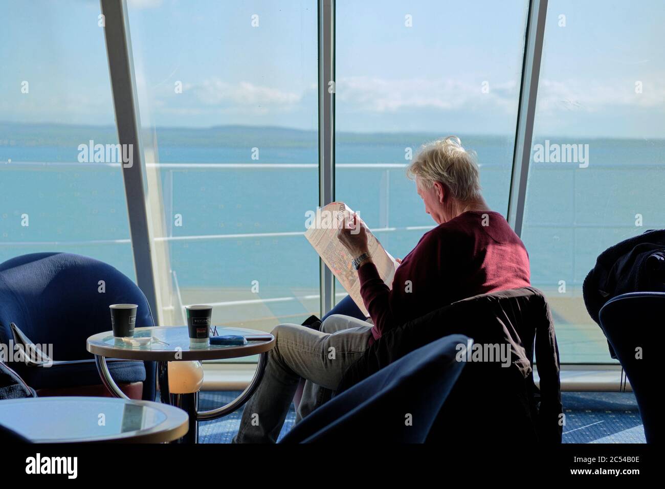 I passeggeri che leggono nella sala Club Class di un traghetto Irish Ferries durante il viaggio da Dublino a Holyhead Foto Stock