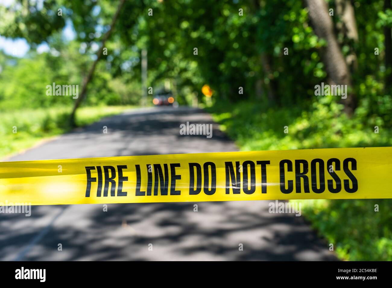 Le linee di emergenza gialla e nera non incrociano il nastro lungo la strada con veicolo di emergenza fuori fuoco sullo sfondo Foto Stock