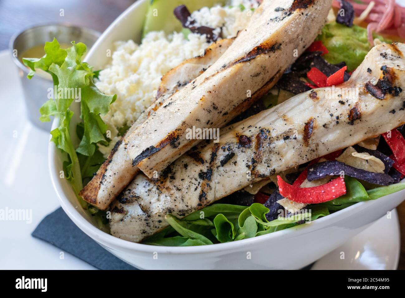 pollo alla griglia focalizzato su un'insalata con formaggio e tortilla multicolore Foto Stock