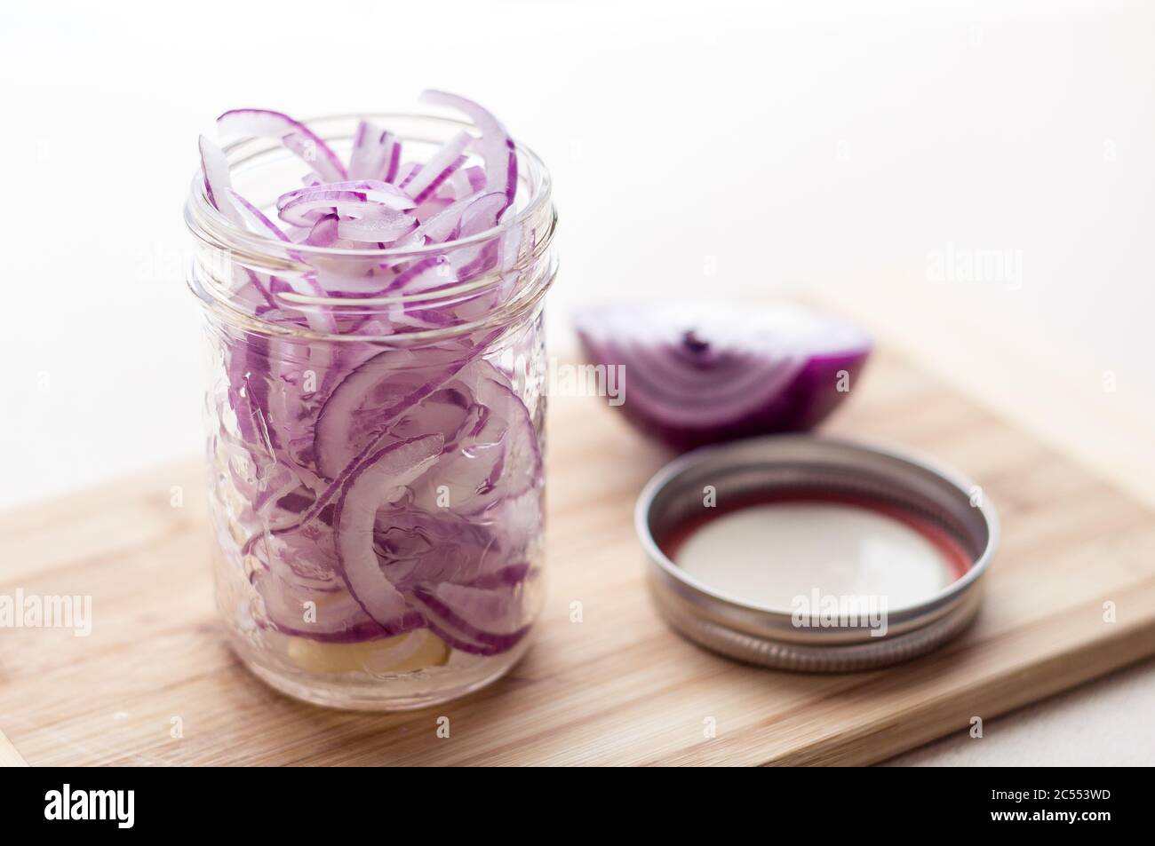 Tagliate le cipolle rosse in un vaso di vetro. Le fette di cipolla tagliate a fette sottili vengono poste in un vaso di vetro e marinate in salamoia con sale e aceto. Alte Foto Stock