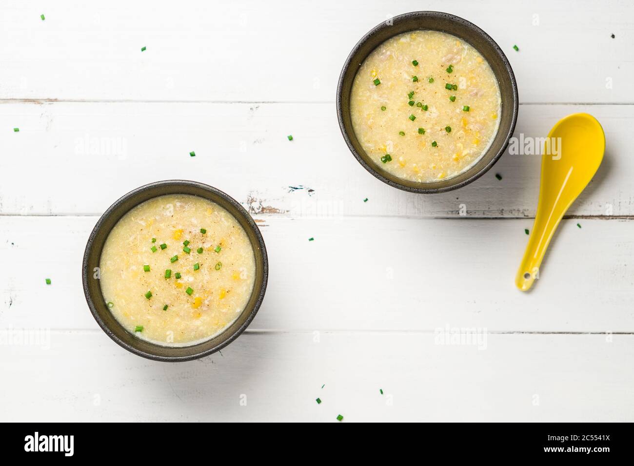 Vista piatta dei contenitori per zuppe di mais. Un piatto di cucina Cantonese spesso servito come antipasto nei ristoranti cinesi. La ciotola della zuppa è su sfondo bianco. Foto Stock