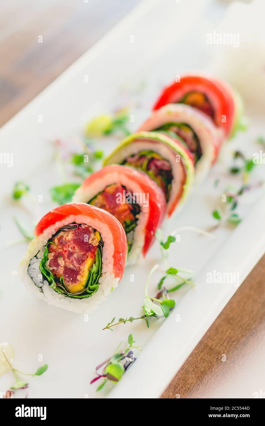 Sushi giapponese uramaki roll. Un sushi in stile uramaki su un piatto bianco. Il pesce e il riso sashimi crudi sono all'esterno mentre nori è all'interno. Questo de Foto Stock