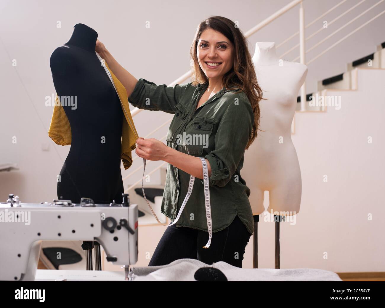 Seamstress lavora a nuovi abiti commissionati da un cliente in un negozio Foto Stock