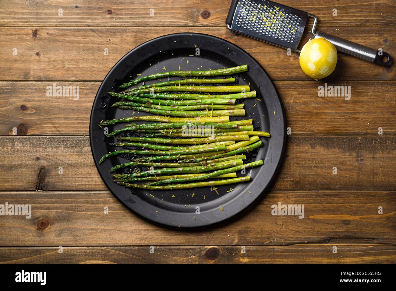 Piastra di asparagi sopra la vista dall'alto. Mangiare cibo sano è facile con questo piatto di vegan fatto in casa; asparagi arrosto con scorza di limone in cima. I veggies sono s. Foto Stock