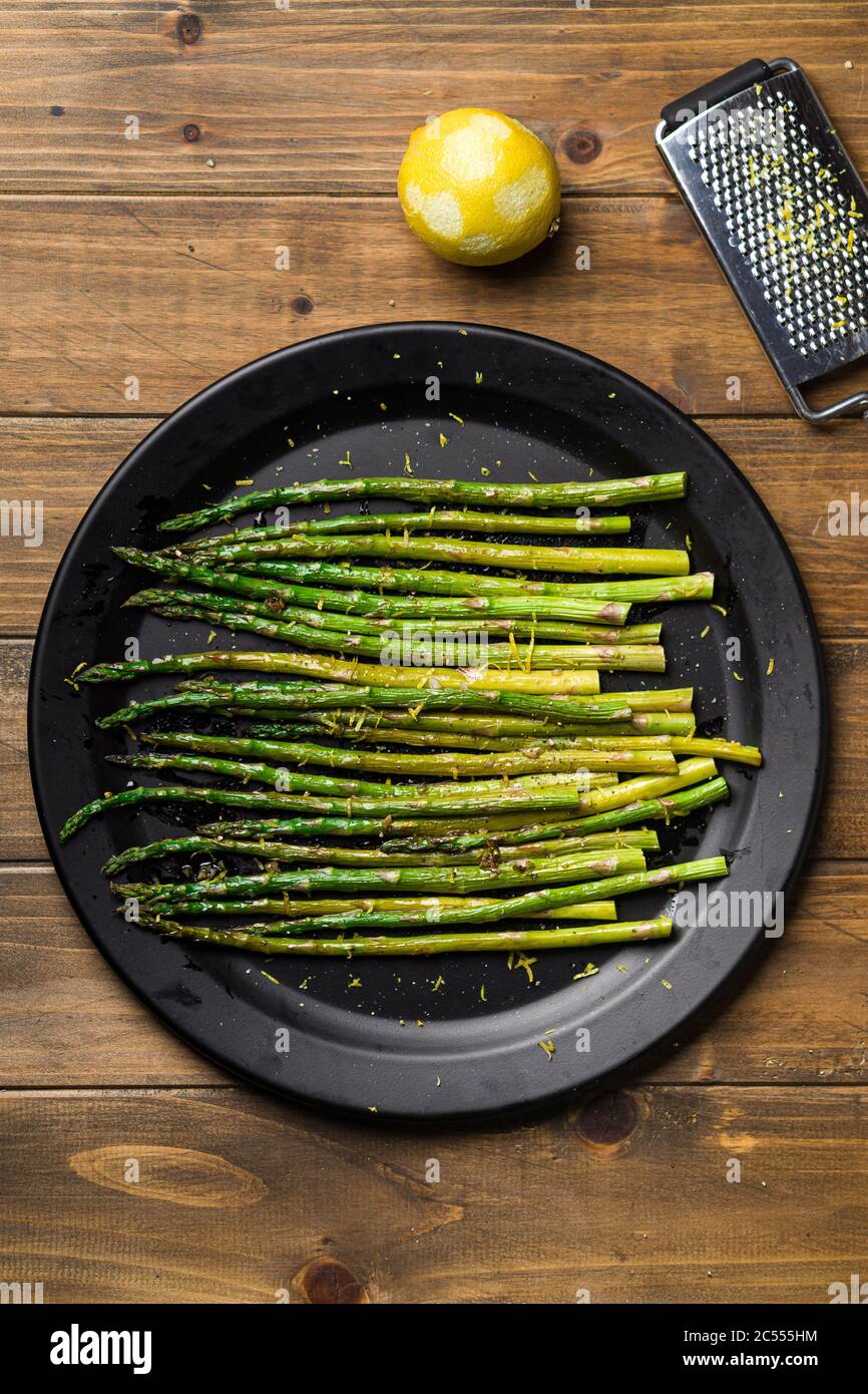 Asparagi cotti dall'alto. Mangiare cibo sano è facile con questo piatto di vegan fatto in casa; asparagi arrosto con scorza di limone in cima. I veggies sono serv Foto Stock