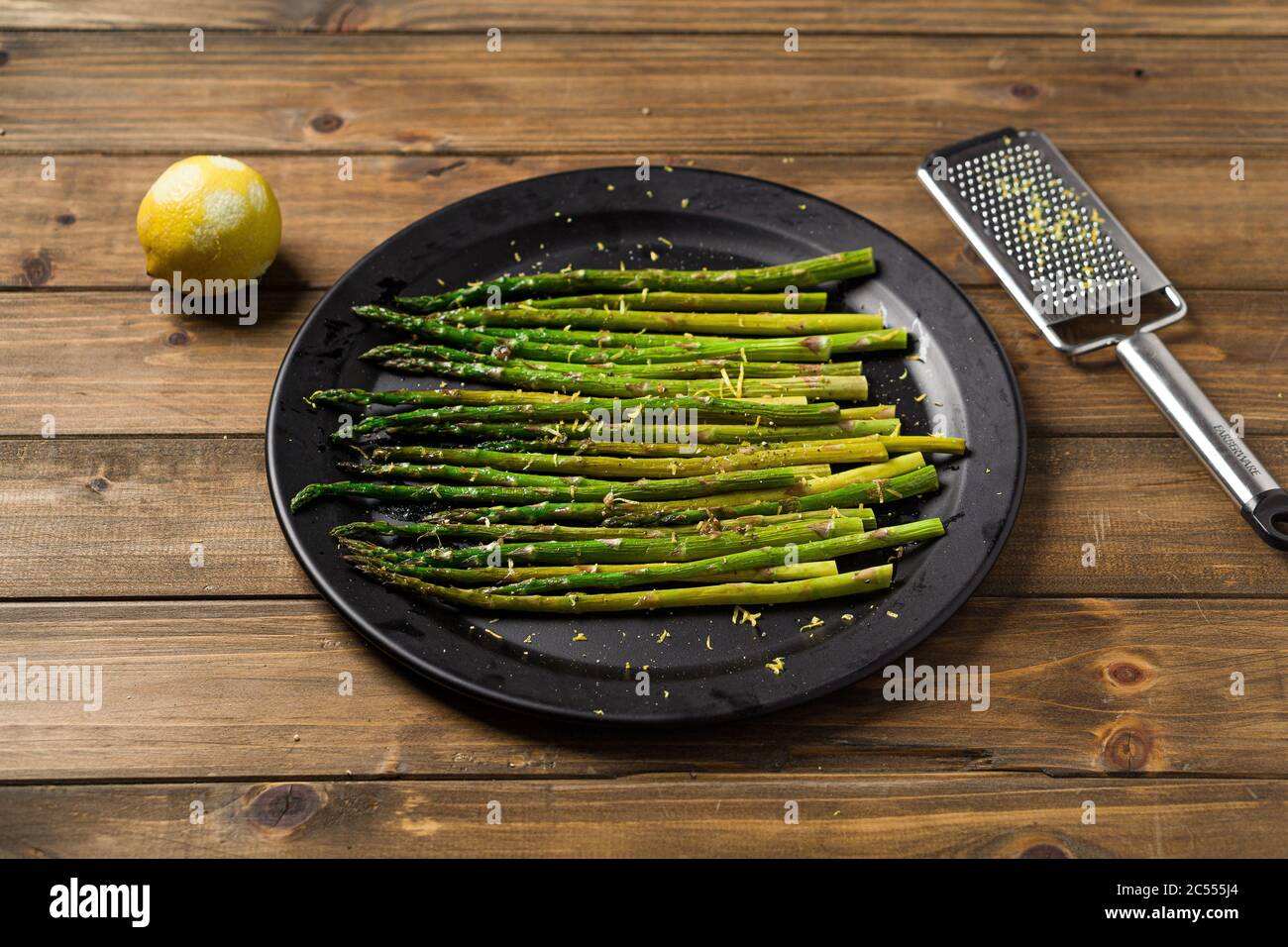 Asparagi di scorza di limone su piatto. Mangiare cibo sano è facile con questo piatto di vegan fatto in casa; asparagi arrosto con scorza di limone in cima. I veggies sono se Foto Stock