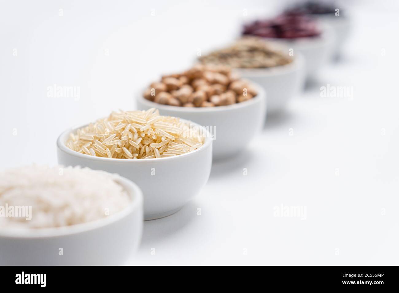 Grani di riso e fagioli sfondo. Profondità di campo poco profonda sui grani di riso basmati in una ciotola bianca con altri tipi di cereali di riso e legumi di fagioli b Foto Stock