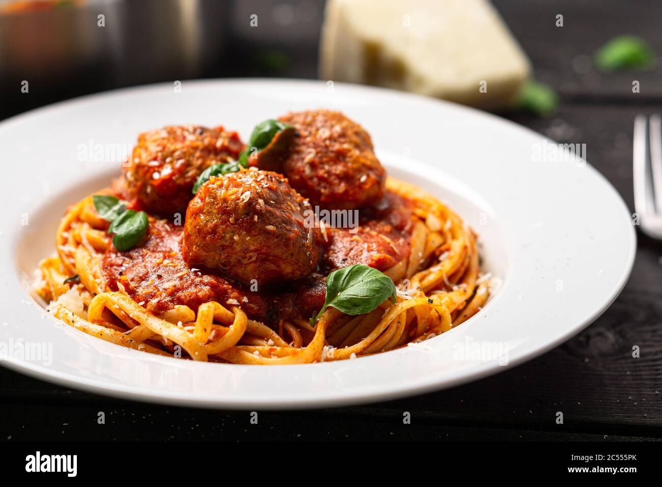 Spaghetti e polpette da vicino. Piatto di pasta italiana servito in piatto bianco su fondo di legno nero. Spaghetti e polpette sono come bolognesi Foto Stock